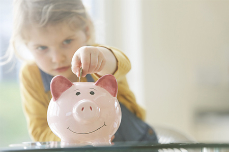 photo of a little girl putting money a piggy bank - Investor.gov