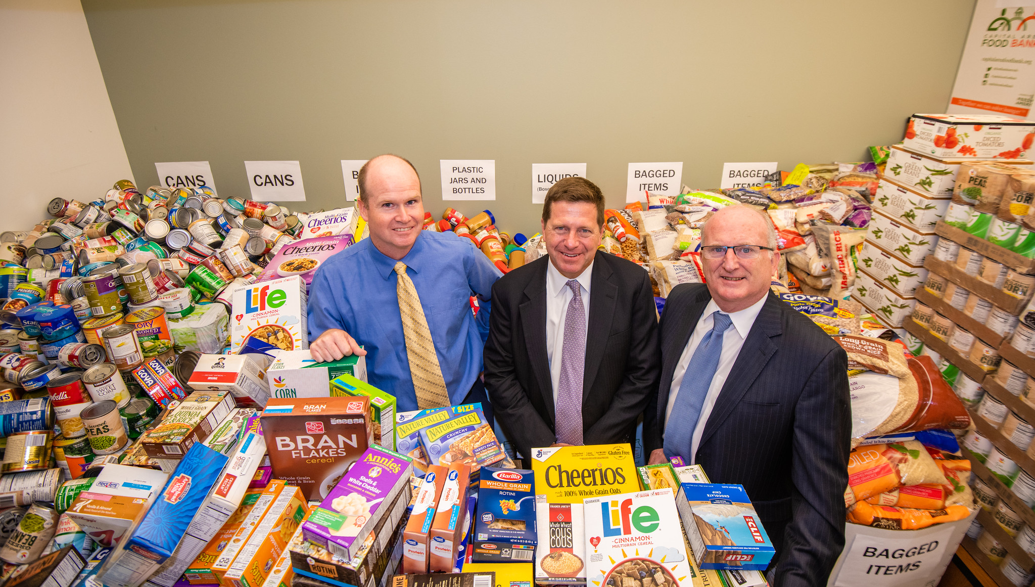 Chairman Jay Clayton and the Office of Public Affairs’ Kevin Callahan (left) and John Nester are surrounded by a mountain of meals – 6 tons, total – in the bountiful Feds Feed Families collection room.